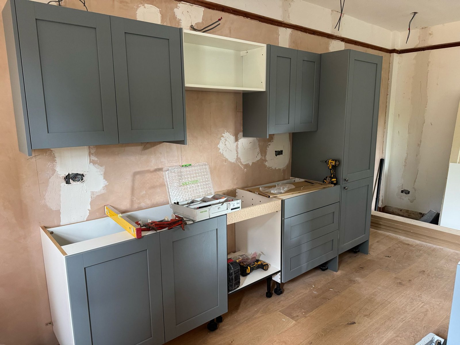Sage blue shaker kitchen cabinets during installation phase